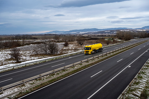 Yellow Tank truck or cistern on a Highway through the rural landscape. Business Transportation And Trucking Industry.