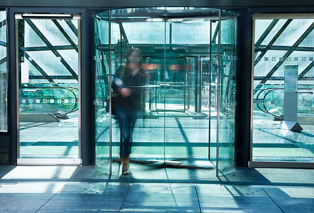 jovem mulher caminhando através de porta giratória, com distorção de movimento - door office business women - fotografias e filmes do acervo