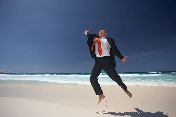 istock senior businessman jumping on deserted beach 182734586