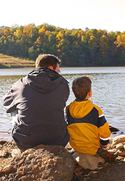 istock Father and son sit together at the lake 182734780