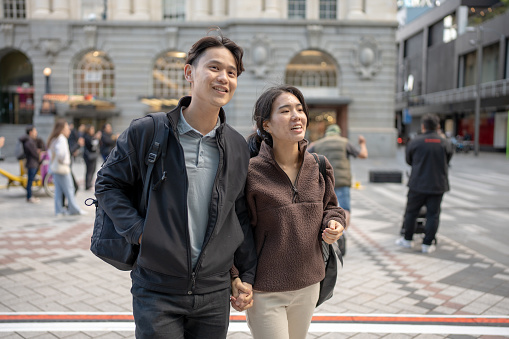 A young asian couple walking in the city holding hands