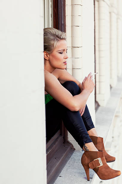istock young blonde smoking candid woman 182737096