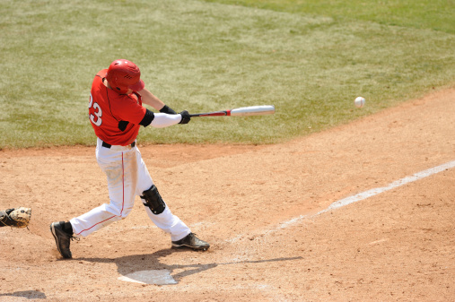 A Baseball play hits a ball during a game.