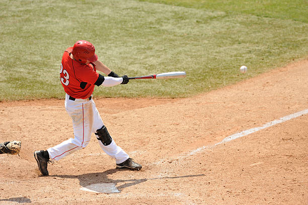 Baseball Batter A Baseball play hits a ball during a game. swinging stock pictures, royalty-free photos & images