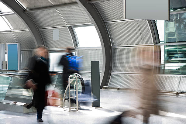 istock Blurred Commuters Walking Through Airport Tunnel With Moving Walkways 182738235