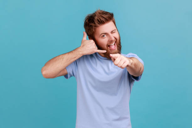 istock Man flirting and pointing at camera with attractive smile, making call me gesture with fingers. 1827389075