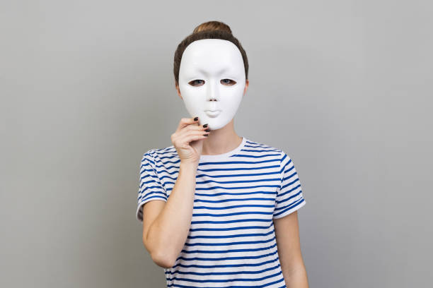 Woman covering her face with white mask, hiding personality, conspiracy and privacy. stock photo