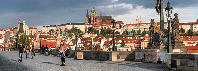 Prague, Czechia - September 16, 2022:  People walk by the artists and historic sculptures across the Charles bridge over the Vlatava River in Czech Republic Czechia Europe