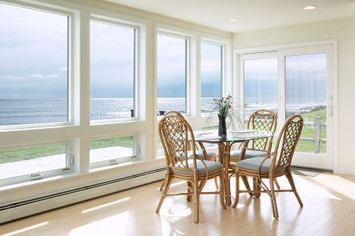 A small breakfast table sits in a sun room over looking the ocean.