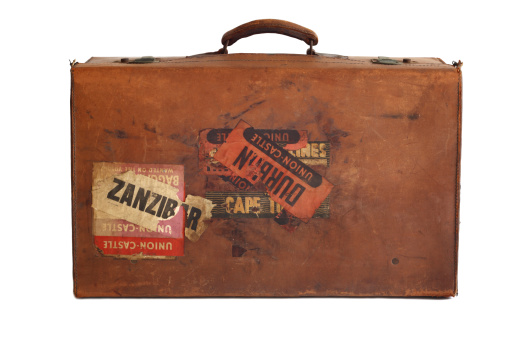 Side view of a well used old leather suitcase used for ocean travel to Africa in mid 1900's. Some stickers visible - shows the words Zanzibar and Durban and Union Castle. Union Castle was a shipping line running between Southhampton and South Africa but stopped operating in 1977.