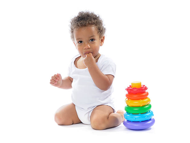 istock Baby Kneeling And Sucking Fingers Next To A Stacker Toy 182741039