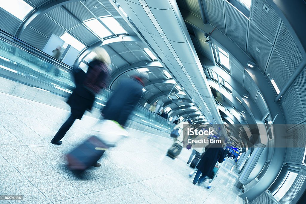 I viaggiatori a piedi giù moderno aeroporto di Tunnel - Foto stock royalty-free di Adulto