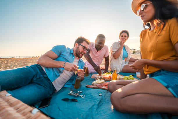 istock Happy Multi-Ethnic People Eating Snacks and Drinking Beer At The Beach 1827423595