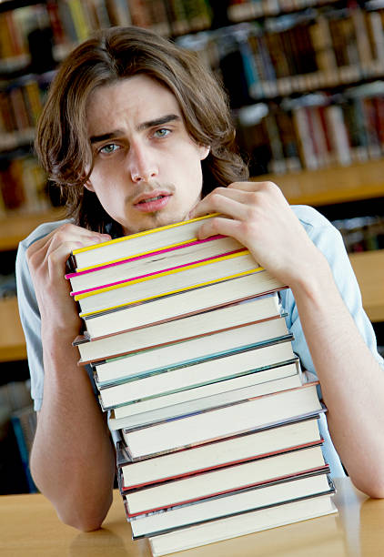istock Young Man with a Stack of Books at the Library 182742430