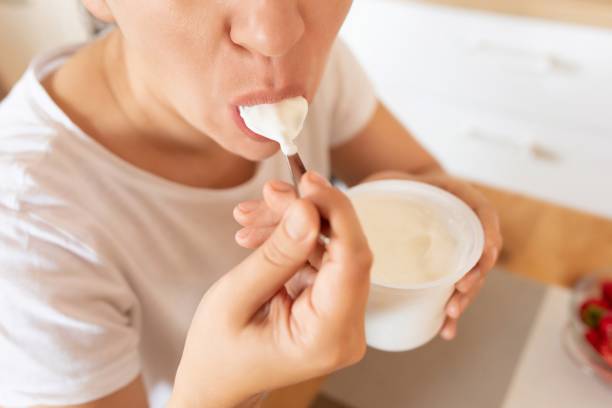 istock Young woman feels hungry and eats sour cream with a spoon 1827424704