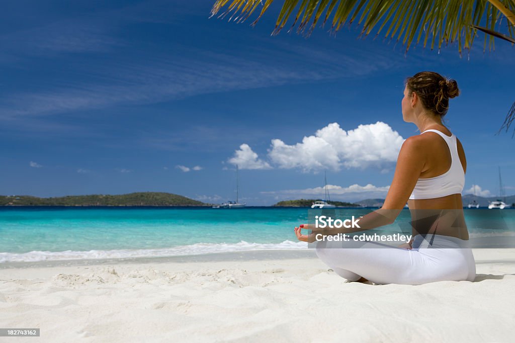 woman doing yoga at the Caribbean beach young woman in white sport outfit practicing yoga under the palm tree at the beach in the Caribbean Caribbean Stock Photo