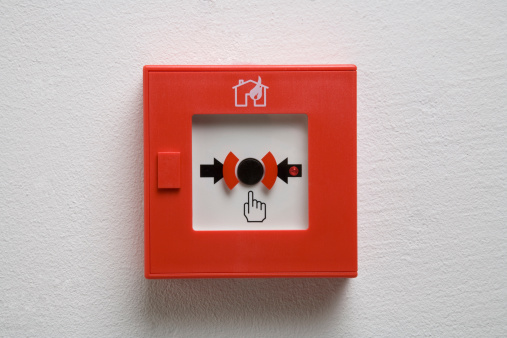 Red fire alarm box on a white wall