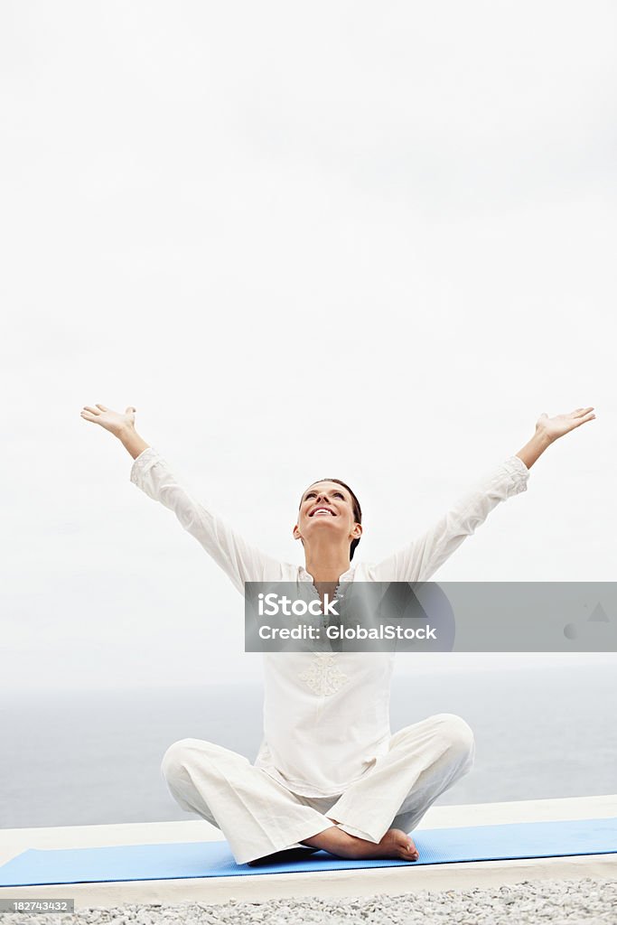 Donna matura felice con le braccia alzate seduto su un tappeto - Foto stock royalty-free di Donne