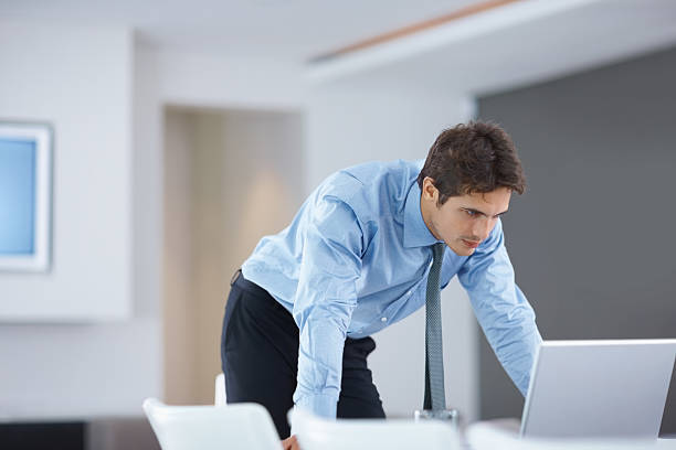 istock Young businessman leaning over a laptop at work 182745522