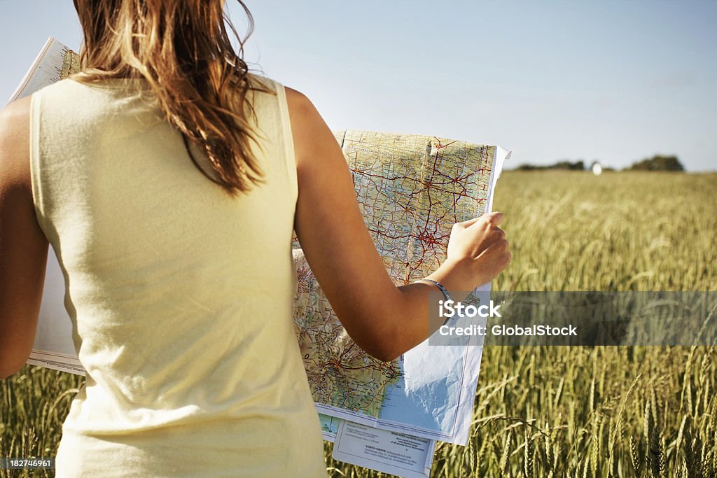 Vue arrière d'une femme avec une feuille de route dans le champ - Photo de Carte routière libre de droits