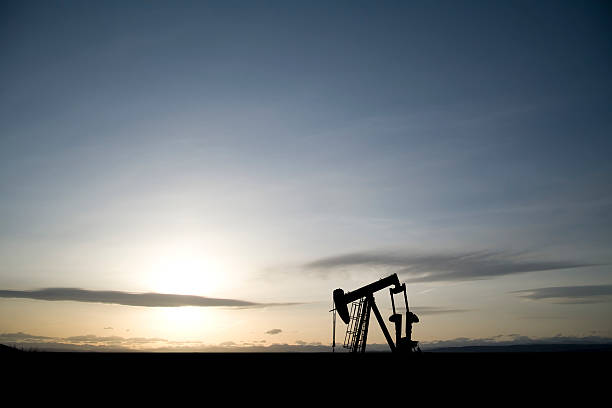 Lone Pumpjack at Dawn A solitary oil and gas pumpjack works against a rising sun. oil pump petroleum equipment development stock pictures, royalty-free photos & images