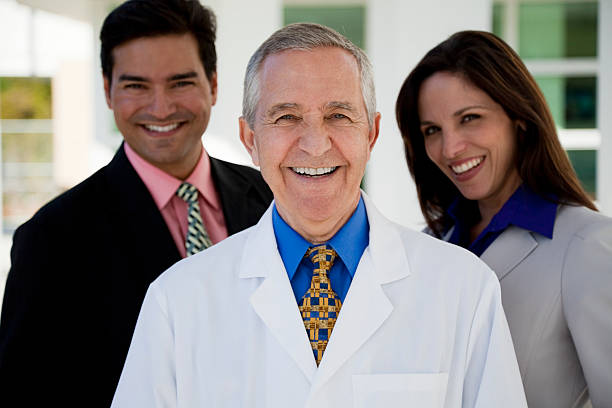 alter mann trägt laborkittel mit zwei geschäftsleute - healthcare and medicine smiling group of people lab coat stock-fotos und bilder
