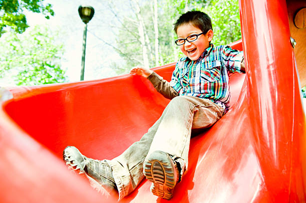 happy boy on red slide stock photo