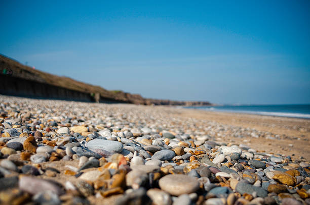 guijarros en una playa con gran cielo azul - shingle beach fotografías e imágenes de stock