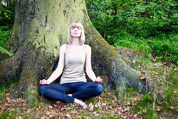 istock woman meditating in front of tree 182748082