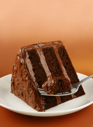 Slice of triple layer chocolate cake with a bite on a fork.More cakey goodness: