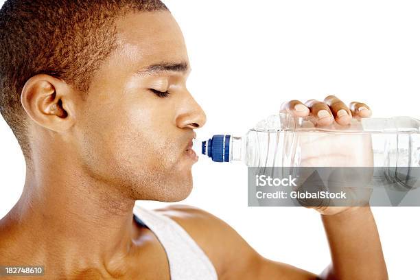 Молодой Человек Питьевой Воды В Бутылках Изолированные Против Белый — стоковые фотографии и другие картинки 20-29 лет