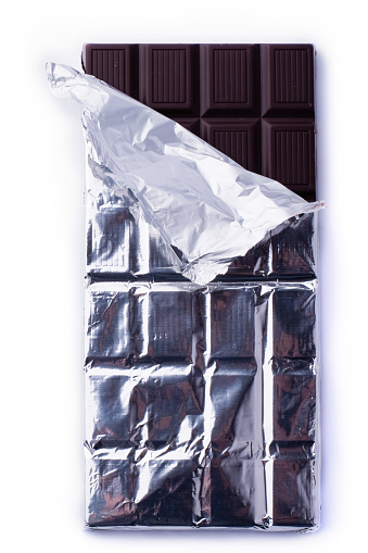 Top view of dark chocolate bars and pieces and the foil wrap on white background
