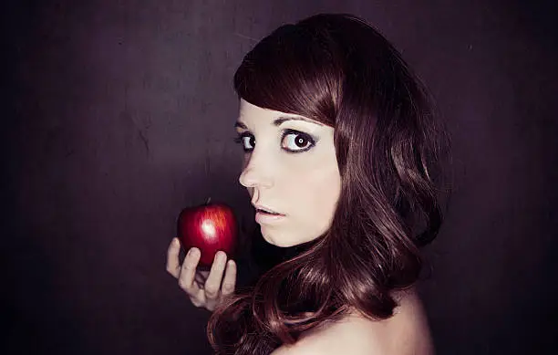 "Portrait of a young woman holding a red apple, looking at the camera with an unsure look on her face.Image is processed from a 16 bit RAW file and profiled in ProPhoto RGB. All my images are professionally retouched.More from this Series:"