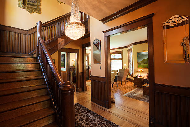 Entryway Foyer and Staircase of Restored Renovated Victorian Home Interior "Subject: The interior foyer or entryway of an old restored Victorian style home, with oriental rugs and period furniture." moulding trim photos stock pictures, royalty-free photos & images