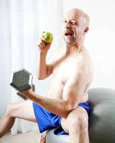 An older man lifts weights and enjoys an apple.