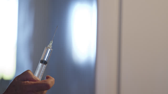 Slow Motion Shot of a Woman Spraying Out Liquid from a Large Syringe