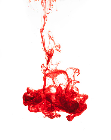 Red colored ink in the water on white background