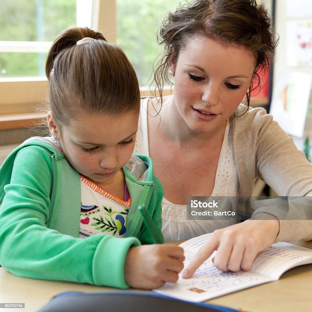 Молодая женщина учитель, работающих с маленькая девочка - Стоковые фото Книга роялти-фри
