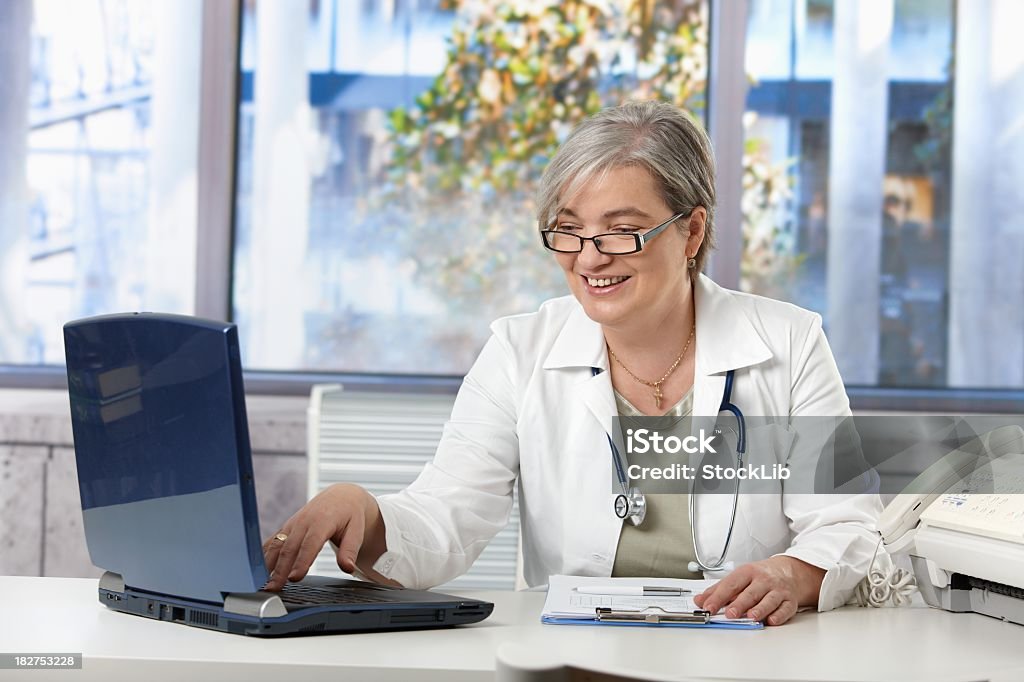 Femmina medico, lavorando su computer portatile - Foto stock royalty-free di 50-54 anni