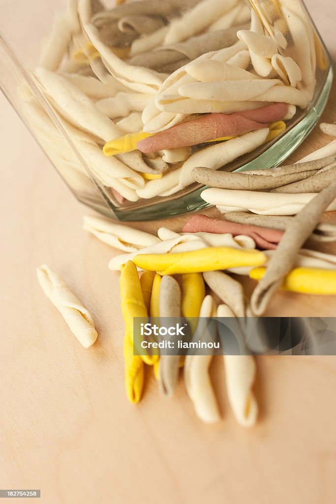 italian pasta colored italian pasta - fusilli on wooden table with glass jar in background Beige Stock Photo