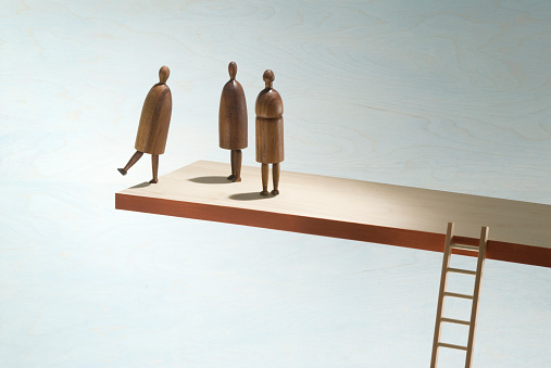 Wooden figures on the edge of a wooden shelf with ladder