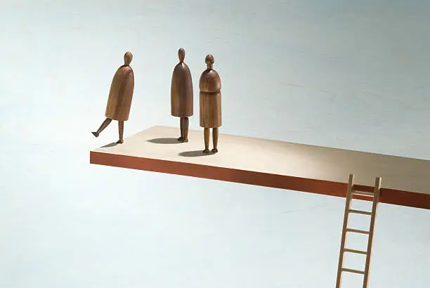 One figure stands at the edge of an elevated plank while other figures look on. 