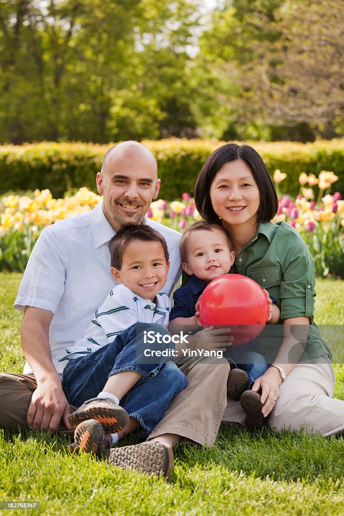 Multiétnico familia de cuatro informal al aire libre en pasto Retrato de jardín - Foto de stock de Familia libre de derechos