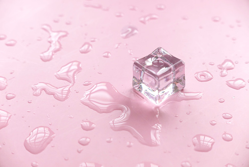 Concept of cold and refreshing. Ice cubes with water drops on a pink background.