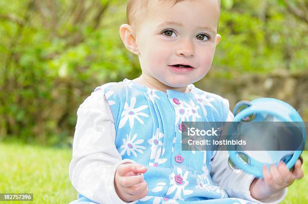 Photo libre de droit de Bébé Fille Assis Dans Le Jardin Parc Tenant Un Tambourin banque d'images et plus d'images libres de droit de 12-17 mois