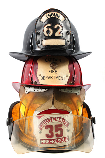 3 firefighter's helmets. One with the black with engine 62. The red with captain, fire department and firefighter's maltese cross coin. The yellow with Lieutenant, 35 and fire-rescue.