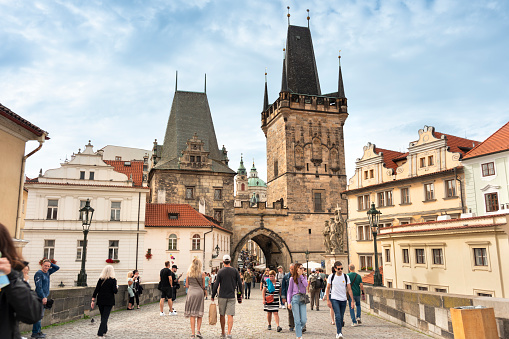 Prague, Czechia - September 13, 2022:  People walk by the artists and historic sculptures across the Charles bridge over the Vlatava River in Czech Republic Czechia Europe