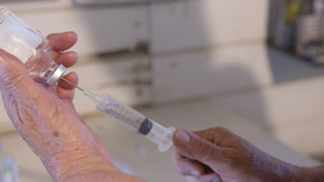 Veterinarian Woman Drawing Fluid from a Glass Vial with syringe