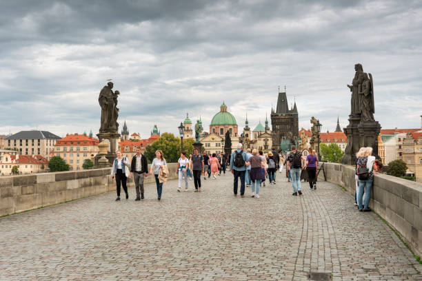 Prague, Czechia - September 13, 2022:  People walk by the artists and historic sculptures across the Charles bridge over the Vlatava River in Czech Republic Czechia Europe