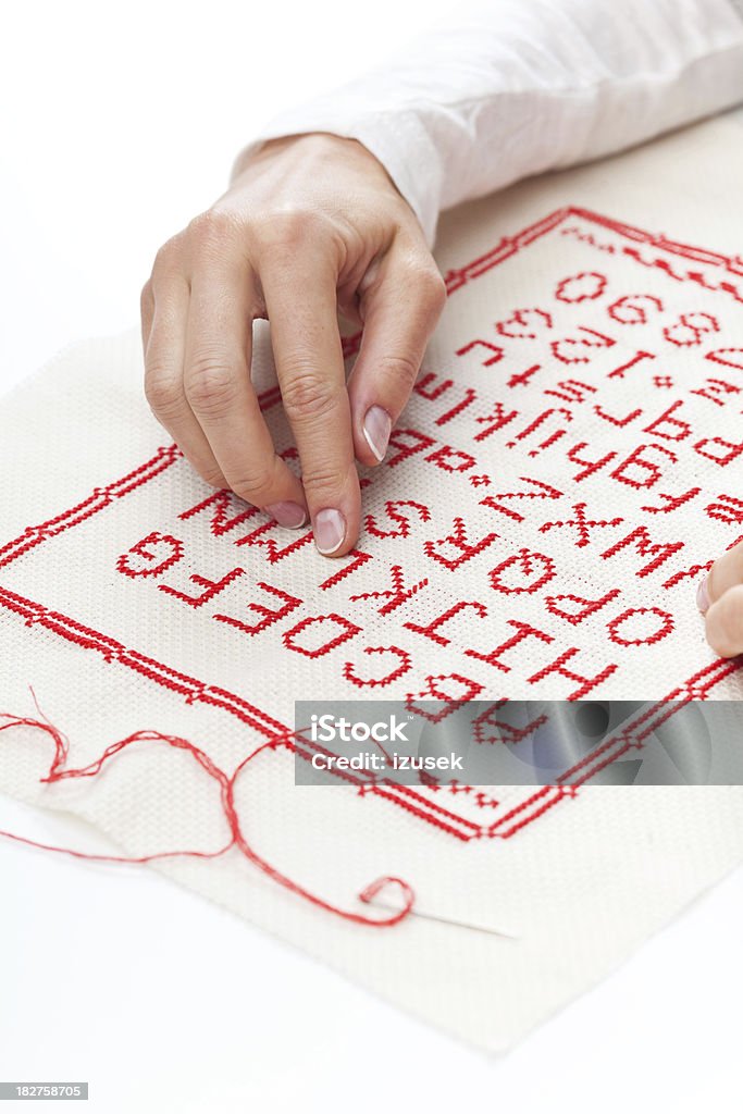Embroideried alphabet Woman hand showing embroideried alphabet onto natural linen. Adult Stock Photo